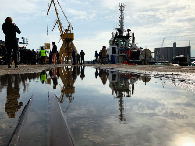 Harbour crane reflected in a puddle at the port location